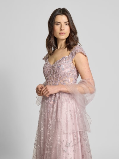 Modelka kobieca nosi schimmerndes Abendkleid aus Tüll mit Stitchings von Unique, efekt błyszczący, linia A, długa sukienka, hafty, tiul, dekolt w serek, długość tyłu w rozmiarze 36: 133 cm, szerokość w rozmiarze 36: 35 cm, różowe odcienie, faktura haftu, widok całej sylwetki z przodu
