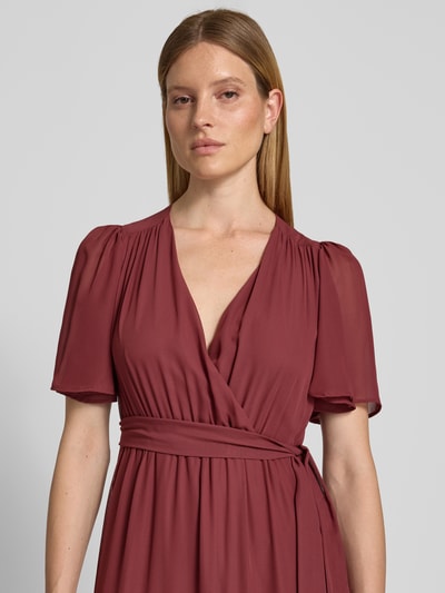 Frauenmodel trägt Abendkleid mit V-Ausschnitt und Bindegürtel von Christian Berg Cocktail in Chiffon, Stufen-Look, Nahaufnahme Oberkörper. Rückenlänge bei Größe 36: 151 cm, Brustweite bei Größe 36: 41 cm, Ärmellänge bei Größe 36: 30 cm.