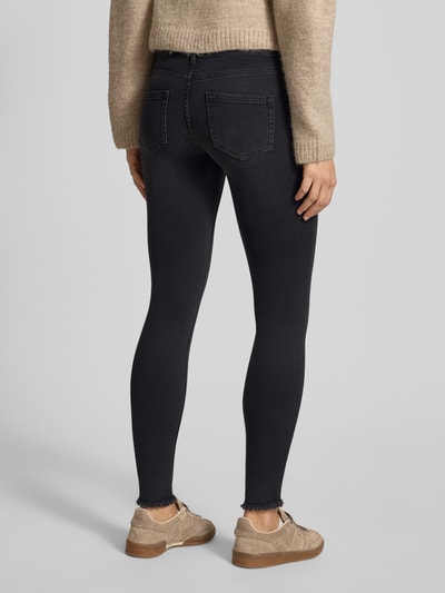 Frauenmodel trägt Stone Washed Skinny Fit Jeans von ONLY aus Baumwollmischung mit Stretch-Anteil, ausgefranste Beinabschlüsse, 5-Pocket-Design, Label-Patch, dunkle Waschung, Ganzkörperansicht Rückansicht.
