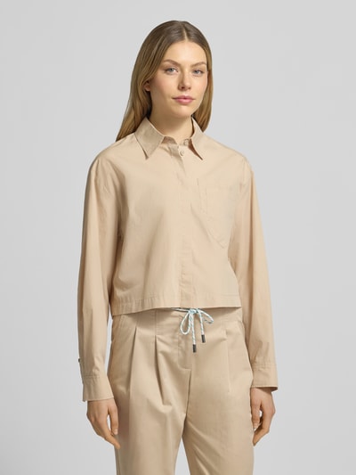 Modelka nosi Boxy Fit Bluse mit Brusttaschen von Marc Cain z bawełny w kolorze beżowym z kołnierzykiem koszulowym i listwą guzikową, brustasza, długość tyłu w rozmiarze 36: 51 cm, długość rękawów w rozmiarze 36: 57 cm, pudełkowy krój; zbliżenie na górną część ciała z przodu.