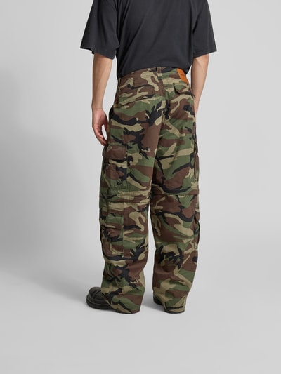 Männermodel trägt Relaxed Fit Cargohose aus Reine Baumwolle von VETEMENTS mit Cargotaschen, Farbton Camouflage, Ganzkörperansicht Rückansicht.