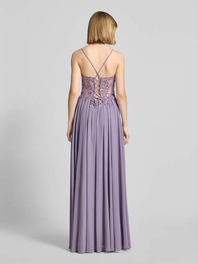 Frauenmodel trägt Abendkleid mit Spitze und Strasssteinbesatz von Mascara aus fliederfarbenem Chiffon, A-Linie, Maxikleid, V-Ausschnitt, rückseitig überkreuzte Spaghettiträger, Rückseitige Schnürung, Haken- und Reißverschluss, Rückenlänge 132 cm, Brustweite 40 cm, Ganzkörperansicht Rückansicht.