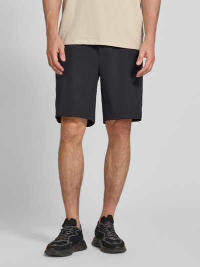 Männermodel trägt Relaxed Fit Cargoshorts mit Label-Schriftzug Modell 'GLOBE CARGO' von BOSS Green, unifarben, Ganzkörperansicht von vorn.