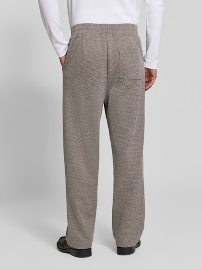 Männermodel trägt Straight Fit Stoffhose aus Baumwoll-Mix von DRYKORN, beige, feine Struktur, Bundfalten, Rückansicht, Ganzkörperansicht von hinten, Innenbeinlänge M 73 cm, Seitentaschen und Gesäßtasche.