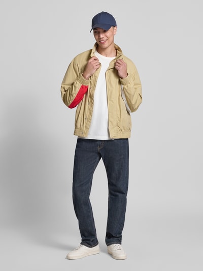 Männermodel trägt Regular Fit Blouson mit Logo-Stitching von Tommy Hilfiger, beige, unifarben, Satin, seitliche Taschen, Ganzkörperansicht von vorne.