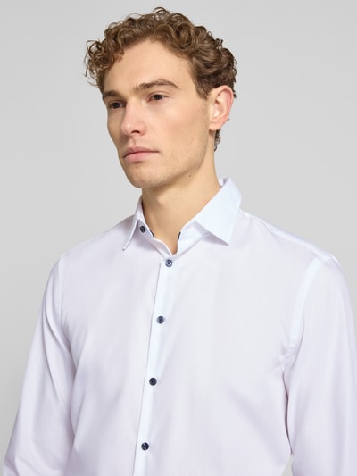 Männermodel trägt Slim Fit Business-Hemd mit Kentkragen von Jake*s, reine Baumwolle, weiße glatte Oberfläche, Nahaufnahme Oberkörper. Rückenlänge 78 cm, Schulterbreite 47 cm, Ärmellänge 63 cm, Knopfleiste mit dunklen Knöpfen bei Größe 39/40.