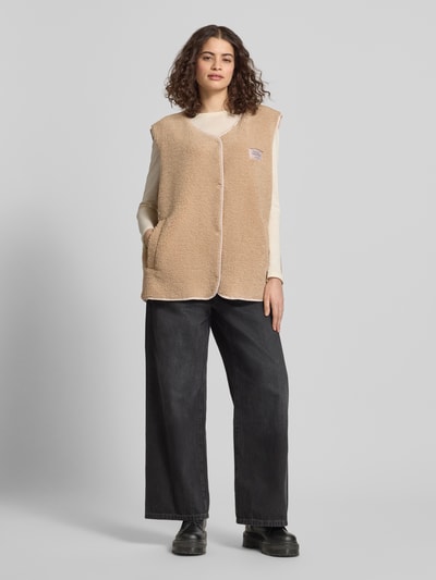 Frauenmodel trägt Fleeceweste mit Label-Detail von Karo Kauer in Beige, Relaxed-Fit, V-Ausschnitt, Knopfleiste, Strukturstoff, Ganzkörperansicht von vorne. Rückenlänge 70 cm, Schulterbreite 48 cm, Brustweite 61 cm bei Größe S.