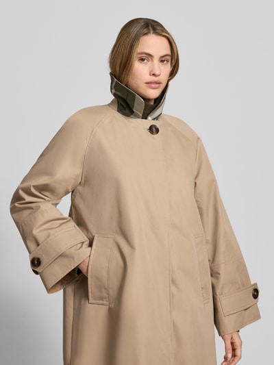 Vrouwenmodel draagt Relaxed Fit lange jas uit katoenmix Model 'KENNEDY' van Barbour in effen kleuren met platte kraag, knoop- en ritssluiting, labelstitching, lange raglanmouwen met trensje, steekzakken en binnenzak; materiaal: katoenmix. Nahaufnahme Oberkörper.