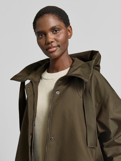 Frauenmodel trägt Parka mit Kapuze Modell 'AKIRA' von g-lab in Oliv mit geradem Schnitt, strukturierter Oberfläche, Nahaufnahme Oberkörper.