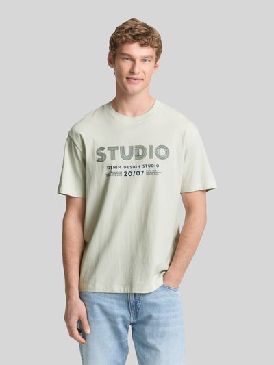 Männermodel trägt Relaxed Fit T-Shirt aus reiner Baumwolle von Tom Tailor Denim, Optik: Unifarben, Label-Print, Rundhals, Kurzarm, Ganzkörperansicht von vorne.