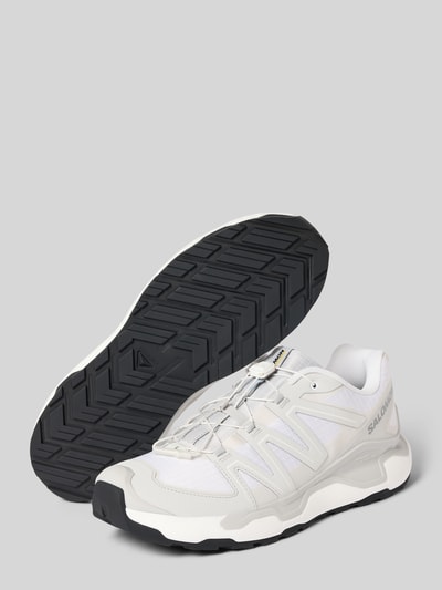 Produktfoto, Sneaker mit profilierter Sohle Modell 'XC ROAM' von Salomon in Weiß mit abgerundeter Spitze, Schnürung und sichtbarem Logo auf grauem Hintergrund