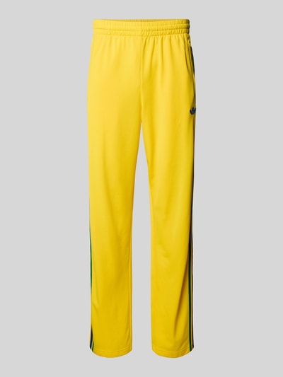 Produktfoto, Straight Fit Sweatpants mit Logo-Stitching Modell 'Firebird' van adidas Originals, geel met steekzakken met ritssluiting, elastische band, binnenbeenlengte maat M 40 cm