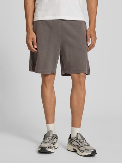 Männermodel trägt Regular Fit Shorts mit elastischem Bund Modell 'Harper' von Carhartt Work In Progress in Braun aus reiner gewachster Baumwolle, Nahaufnahme Oberschenkel, Kontext: Herren Shorts, Bundweite 44 cm, Innenbeinlänge 17 cm, Größe M.
