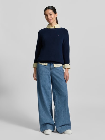 Vrouwenmodel draagt Regular Fit Pullover aus reiner Baumwolle van Tommy Hilfiger in effen donkerblauw, met logo-stiksel, ronde hals en lange mouwen, gemaakt van geribbelde zuivere katoen, geheel lichaamsaanzicht van voren.
