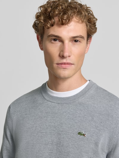 Männermodel trägt grauen Regular Fit Pullover aus Baumwoll-Mix von Lacoste, dezente Struktur, Nahaufnahme Oberkörper. Herren Pullover von Lacoste