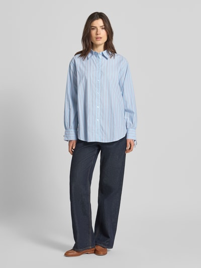 Kobiece modelka nosi Oversized Hemdbluse aus reiner Baumwolle von Tom Tailor Denim, wielokolorowy wzór w paski, popelina, szeroki krój, naszywka z logo, widok całej sylwetki z przodu.