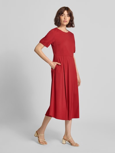 Frauenmodel trägt Midikleid mit Rundhalsausschnitt von MORE & MORE in Rot, A-Linie, aus Baumwoll-Mix mit Stretch, Ganzkörperansicht von vorne.