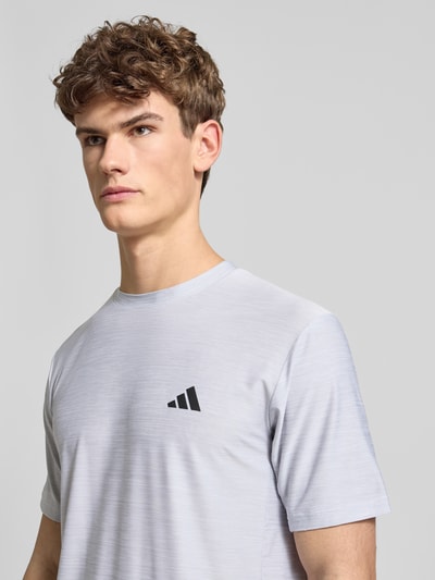 Männermodel trägt T-Shirt mit Label-Print von adidas Training, heller Material-Mix mit Stretch-Anteil, Regular-Fit, Nahaufnahme Oberkörper.