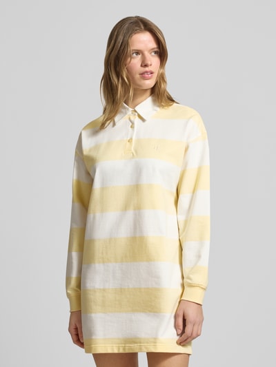Frauenmodel trägt Regular Fit Minikleid mit Polokragen Modell 'Varsity' von Calvin Klein Jeans aus reiner Baumwolle, gelb-weiße Blockstreifen, langärmeliges Design mit Logo-Stitching und elastischen Ärmelabschlüssen, Nahaufnahme Oberkörper.