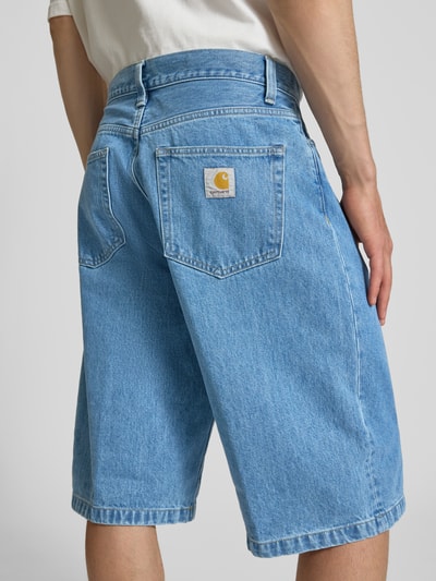 Männermodel trägt Jeansshorts mit Eingrifftaschen Modell 'Langdon' von Carhartt Work In Progress, hellblau, reine Baumwolle, Ganzkörperansicht Rückansicht.