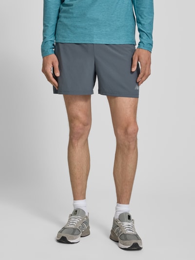 Männermodel trägt Shorts mit elastischem Bund und Logo von New Balance in Grau, Regular Fit, mit Tunnelzug und Logo, Nahaufnahme Oberschenkel.