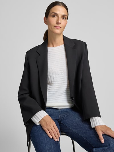 Frauenmodel trägt Strickpullover mit Strukturmuster von Emporio Armani in Weiß, kombiniert mit schwarzem Blazer und blauer Jeans, Nahaufnahme Oberkörper. Damen Strickpullover, taillierte Passform, Rundhalsausschnitt, langärmelig, Rückenlänge 35 cm, Ärmellänge 57 cm.