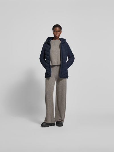 Frauenmodel trägt Daunenjacke mit Kapuze von Moose Knuckles in Dunkelblau, Material-Mix mit Stretch-Anteil, taillierter Schnitt, Reißverschluss, Reißverschlusstaschen, Ganzkörperansicht von vorne.