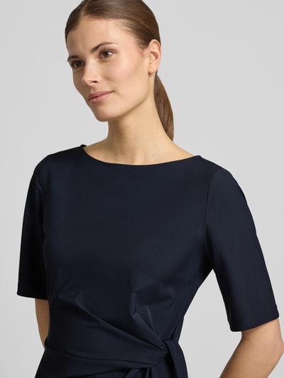 Vrouwenmodel draagt midi-jurk met knoopdetail van Milano Italy, donkerblauw, materiaalmix met stretch, getailleerd, ronde hals, nahopname bovenlichaam.
