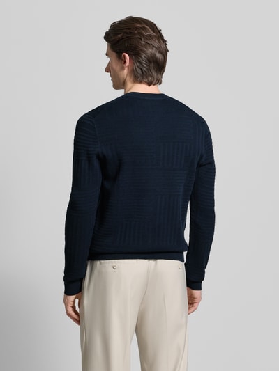 Męski model nosi granatowy Strickpullover mit gerippten Abschlüssen Modell 'Raikon' od JOOP! Collection, krój regular fit, bawełna, widok całej sylwetki od tyłu.