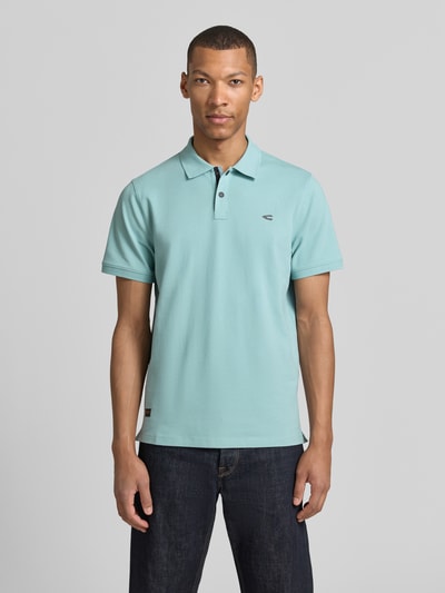 Männermodel trägt Regular Fit Poloshirt in unifarbenem Design van camel active, mix van katoen en elastaan, logoprint, knoopsluiting, ruglengte maat M 70 cm, effen lichtblauw, korte mouwen, ganzkörperansicht van voren.