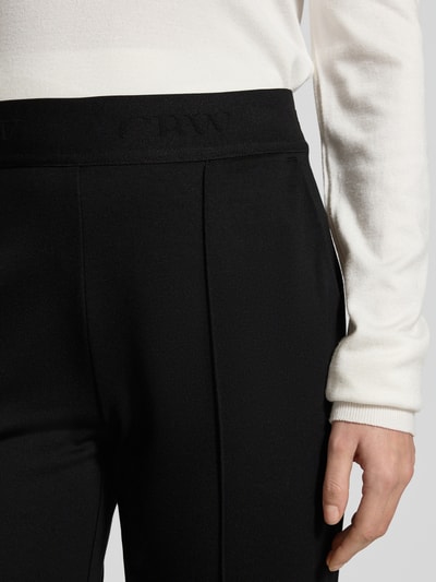 Männermodel trägt czarne Stoffhose mit elastischem Bund von Christian Berg Woman, gładka faktura, francuskie kieszenie, detal pasa, Nahaufnahme Oberkörper.