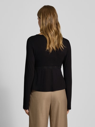 Vrouwenmodel draagt Slim Fit Langarmshirt uit viscosemix model 'SINI' van Only in wikkeloptiek met kantdetail, labelstiksel, diepe V-hals, zwarte kleur, lange mouw, materiaal met gladde textuur, zicht op achterkant, volledige lichaamsweergave rugaanzicht.