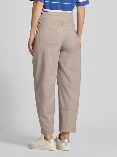 Männermodel trägt Regular Fit Stoffhose mit Eingrifftaschen Modell 'OPHELIA' von Cambio, jasny beż, skrócone nogawki, krój regular fit, elastyczny pas, wpuszczane kieszenie, szerokość w rozmiarze 36: 42 cm, długość wewnętrzna nogawki w rozmiarze 36: 69 cm, Ganzkörperansicht Rückansicht.
