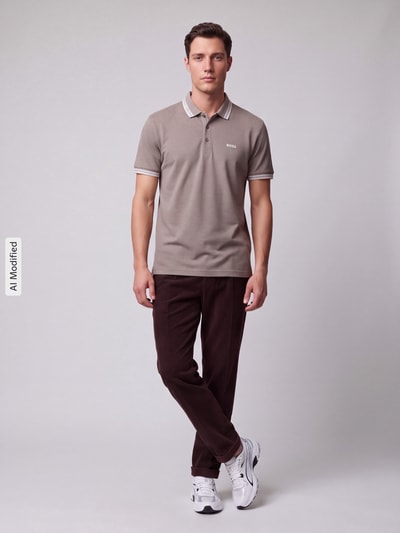 Männermodel trägt Regular Fit Polokragen aus reiner Baumwolle Modell 'PADDY' von BOSS Green, beige, weiße Details, Ganzkörperansicht von vorne, KI-modifiziertes Bild.