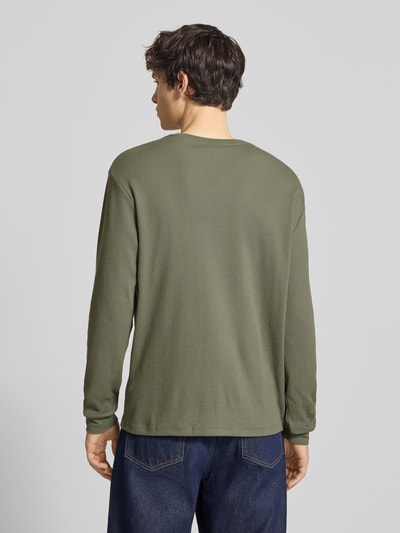 Męski model nosi Regular Fit Langarmshirt aus Baumwoll-Mix von Calvin Klein Jeans, efekt: jednolity kolor, krój regular fit, mieszanka bawełny, naszywka z logo, okrągły dekolt, długi rękaw, Ganzkörperansicht Rückansicht.