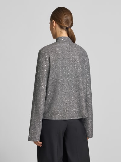Vrouwenmodel draagt Langarmbluse mit schimmernder Optik van JAKE*S WOMAN COLLECTION in zilvergrijs met structuur, mock neck, hoge halslijn, lange mouwen, schimmerende textuur, geheel achteraanzicht.