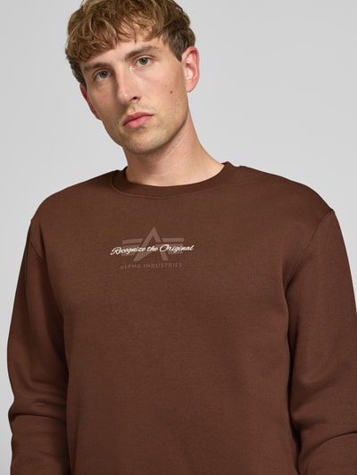 Männermodel trägt Regular Fit Sweatshirt aus Baumwoll-Mix mit Label-Detail von Alpha Industries, braun, Nahaufnahme Oberkörper.