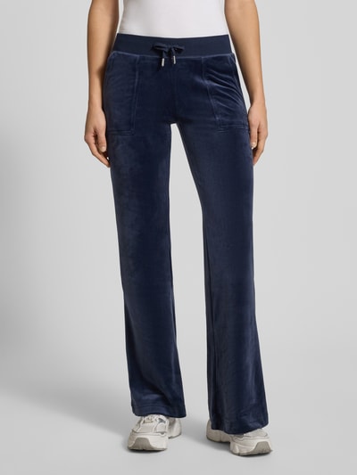 Frauenmodel trägt Low Rise Sweatpants mit elastischem Bund Modell 'LAYLA' von Juicy Couture aus blauem Baumwoll-Mix mit Stretch-Anteil, Flared-Cut, Eingrifftaschen, Innenbeinlänge bei Größe S 39 cm, Nahaufnahme Oberkörper.