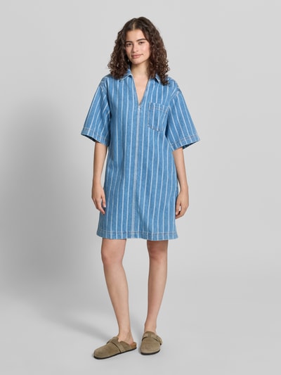 Frauenmodel trägt Relaxed Fit Jeanskleid aus reiner Baumwolle - Special Drop von Marc O'Polo Denim in gestreifter Denim-Optik, Mini-Länge, V-Ausschnitt, Hemdblusenkragen, Ganzkörperansicht von vorne.