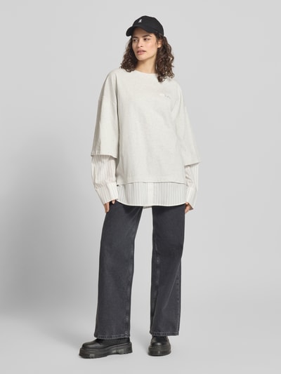 Frauenmodel trägt Oversized Longsleeve in Layering-Optik von Karo Kauer aus reiner Baumwolle mit Label-Stitching, Rundhalsausschnitt, helle Farben, Ganzkörperansicht von vorne.