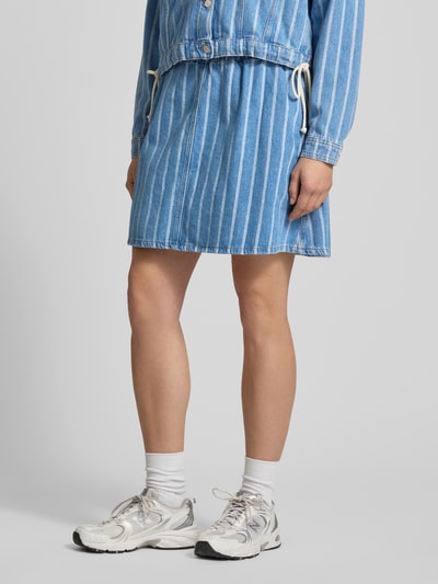 Frauenmodel trägt Regular Fit Mini-Rock aus reiner Baumwolle von Marc O'Polo Denim, blau-weiß gestreift, Twill-Textur, Nahaufnahme Unterkörper.