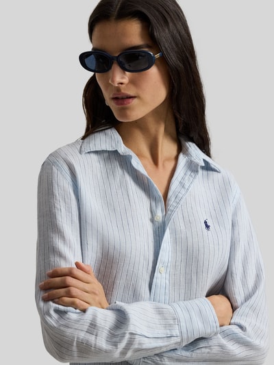 Frauenmodel trägt Hemdbluse aus reinem Leinen von Polo Ralph Lauren mit feinem Streifenmuster und Label-Stitching, Nahaufnahme Oberkörper.