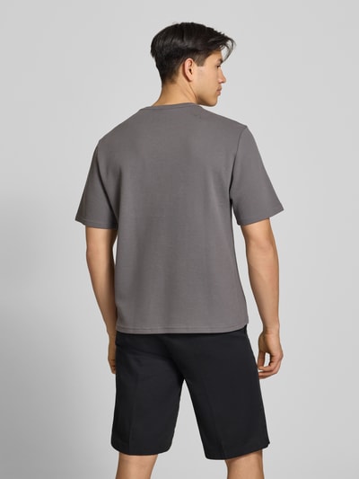Männermodel trägt T-Shirt mit Label-Stitching von REVIEW in Grau mit Waffelstruktur, gerader Schnitt, Rückenansicht, Ganzkörperansicht Rückansicht.