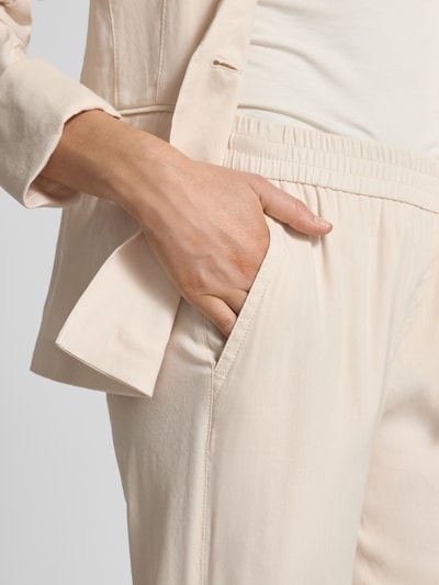 Frauenmodel trägt Straight Fit Leinenhose mit Viskose-Anteil von Marc Cain in Beige, mit elastischem Bund und Gesäßtaschen, Nahaufnahme Oberkörper