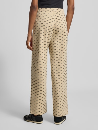 Frauenmodel trägt Wide Leg Sweatpants aus Baumwoll-Mix von Armani Exchange in Beige mit Allover-Logo-Print und gesmoktem Bund, Ganzkörperansicht Rückansicht.
