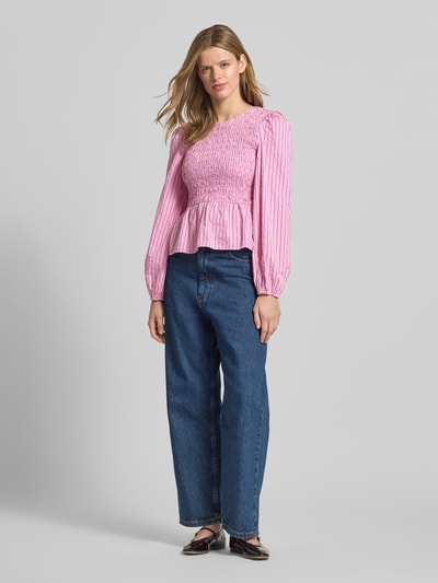 Kobiecy model nosi Slim Fit Bluse aus Baumwoll-Mix von Marc O'Polo Denim, efekt: wzór na całej powierzchni, krój slim fit, okrągły dekolt, głęboki dekolt na plecach, zapięcie: wiązanie, długi rękaw, wykończenie: marszczenie, mieszanka bawełny, kolor różowy z białym wzorem, tekstura lekko marszczona, Ganzkörperansicht von vorne.