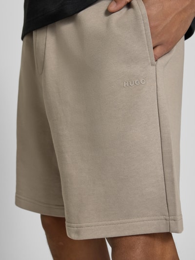 Männermodel trägt Regular Fit Sweatshorts aus reiner Baumwolle Modell 'DAYONO' von HUGO, efekt: jednolity kolor, krój regular fit, nadruk z logo, elastyczny ściągacz z tunelem, wpuszczane kieszenie, wykończenie materiału: dzianina dresowa, materiał: bawełna, Nahaufnahme uda