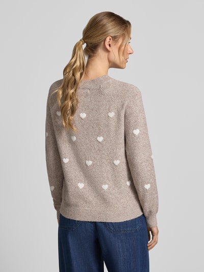 Frauenmodel trägt Regular Fit Pullover mit Rundhalsausschnitt Modell 'DOFFY' von VERO MODA, beige mit weißen Herzmustern, Textur grob gestrickt, Ganzkörperansicht Rückansicht, Damen Pullover von VERO MODA.