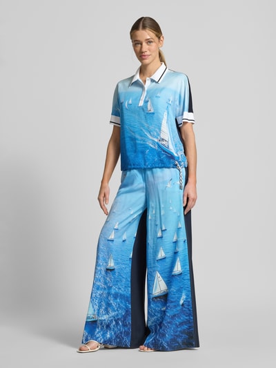 Frauenmodel trägt Wide Fit Stoffhose aus reinem Lyocell von Marc Cain mit Allover-Motiv-Print in Blau, Elastischer Bund, Ganzkörperansicht von vorne.