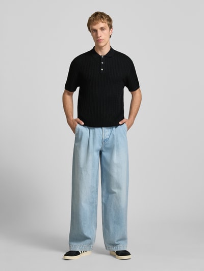 Männermodel trägt Slim Fit Strick-Poloshirt mit Zopfmuster Modell 'EMIL' von Jack & Jones in Schwarz, Baumwoll-Mix, Ganzkörperansicht von vorne.